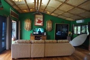a living room with a couch and a green wall at The Parrot Inn Kanchanaburi in Kanchanaburi