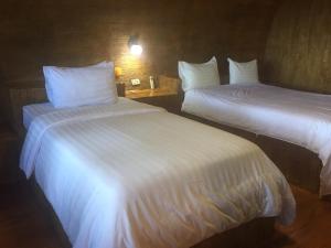 2 Betten in einem Hotelzimmer mit weißer Bettwäsche in der Unterkunft Ban Tawansongfa in Lang Suan