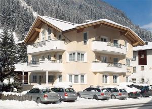 a large apartment building with cars parked in the snow at Ferienhaus & Apart Post in See