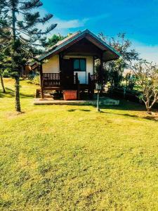 una pequeña casa en un campo con un patio de césped en นุชจนาถรีสอร์ท วังน้ำเขียว en Wang Nam Khieo