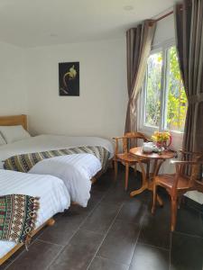 a room with two beds and a table and a window at LẠC DƯƠNG TIÊN CẢNH (BULGALOW) in Xuan An