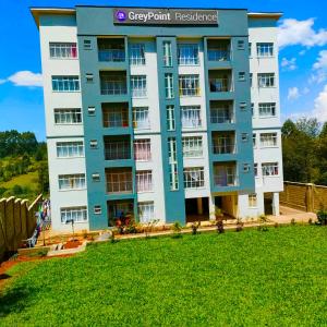 a blue and white apartment building with a green lawn at Cossy homes kericho grey point in Kericho