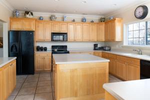 a kitchen with wooden cabinets and a black refrigerator at Family Getaway-Hot Tub, Ice Castles & Tubing HS home in Midway