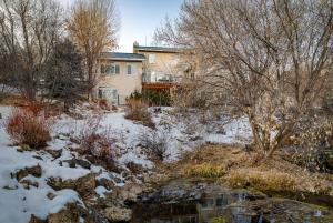 una casa en la nieve junto a un arroyo en Family Getaway-Hot Tub, Ice Castles & Tubing HS home, en Midway