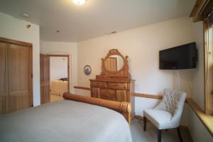 1 dormitorio con cama, espejo y silla en Family Vacation-Heated In Out Pool, Tubing & Ice Skating 719 townhouse, en Midway