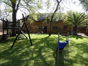 a playground with a swing set in a yard at Weltevrede Lodge - Self Catering Houses in Marloth Park