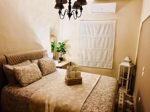 a bedroom with a bed with a chandelier and a window at Traditional house of 1898 in the heart of old town of Nafplio in Nafplio