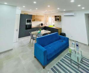 Un sofá azul en una sala de estar con cocina. en Spacious and beautiful flat in Gzira, en Il-Gżira