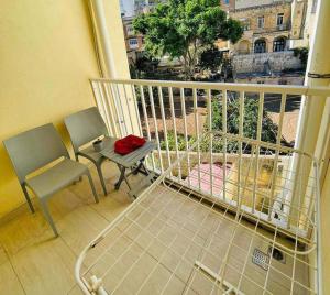 balcón con mesa, silla, mesa y sillas en Spacious and beautiful flat in Gzira, en Il-Gżira
