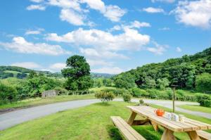 a wooden picnic table in the grass near a road at Pandy Barn Berriew in Welshpool