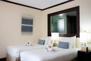 Duas camas brancas num quarto com um espelho em Parasol Blanc em Luang Prabang