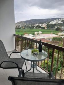 uma mesa numa varanda com um copo de vinho em Klimataria B2 em Pissouri