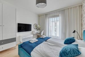 ein weißes Schlafzimmer mit einem großen Bett mit blauen Kissen in der Unterkunft Julia by Q4Apartments - close to the beach in Danzig