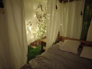 een slaapkamer met een bed met witte gordijnen en een boom bij en attente in Issoudun