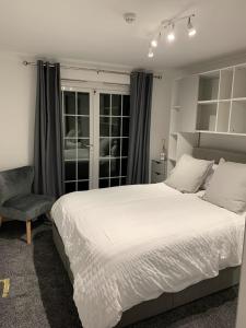 a bedroom with a large white bed and a chair at The Albany Apartments in St Peter Port