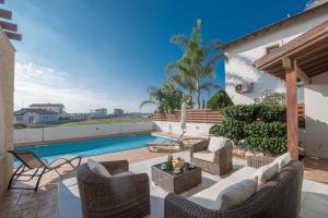 eine Terrasse mit Korbmöbeln und einem Pool in der Unterkunft Kymma Villas by the Sea in Ayia Napa