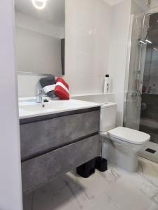 a white bathroom with a sink and a toilet at Appartamento vista oceano a pochi passi dal mare in Playa Fañabe