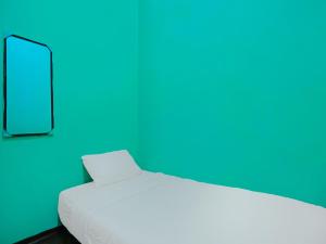 a white bed in a room with a blue wall at SPOT ON 92186 Penginapan Lorra in Nagoya