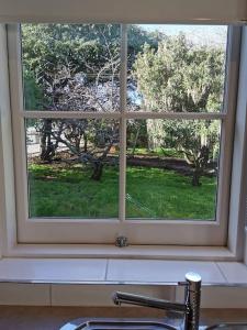 a window over a sink with a view of a yard at The Shoemaker's Cottage in Richmond