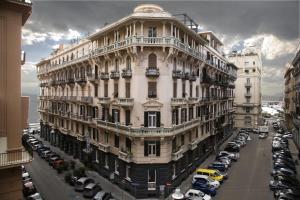 un gran edificio blanco con coches aparcados en un aparcamiento en Rex Lifestyle Hotel, en Nápoles