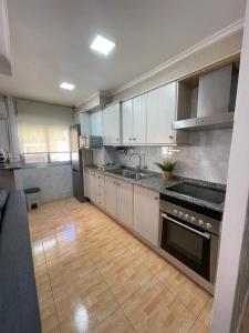 a large kitchen with white cabinets and a wooden floor at UIM Mediterraneo Virgen del Carmen 1 Wifi in Puerto de Sagunto