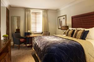 ein Schlafzimmer mit einem großen Bett, einem Schreibtisch und einem Stuhl in der Unterkunft The Arden Hotel Stratford - Eden Hotel Collection in Stratford-upon-Avon