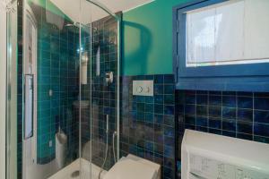 ein blau gefliestes Bad mit einem WC und einer Dusche in der Unterkunft Cala Azzurra a Fetovaia - Goelba in Fetovaia