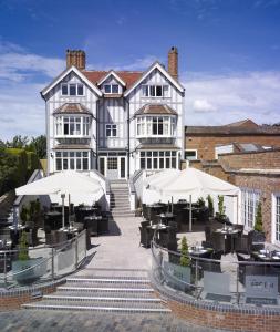 a large building with tables and umbrellas in front of it at The Arden Hotel Stratford - Eden Hotel Collection in Stratford-upon-Avon