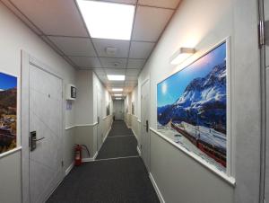 un couloir dans un immeuble de bureaux avec des affiches sur les murs dans l'établissement Railway Hotel, à Almaty