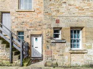 a brick building with a white door and windows at Riding Cottage - Uk37449 in Pateley Bridge