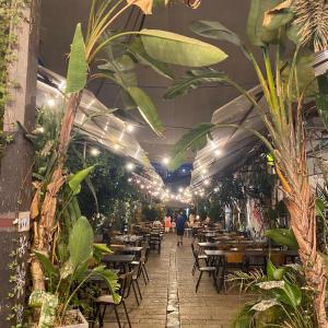 een restaurant met tafels, stoelen en planten bij סוויטת סטודיו במתחם נוֺגה in Tel Aviv