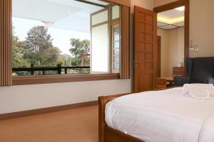 a bedroom with a bed and a large window at Suanphung Bonsai Village in Ban Bo Wi