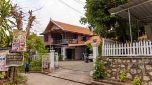 a house with a white fence and a sign in front of it at Mao Pha Sok Guesthouse in Luang Prabang