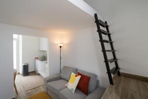 sala de estar con sofá y escalera en la pared en Tia Anica House II - apartment with terrace in central Fuseta beach village, en Fuseta