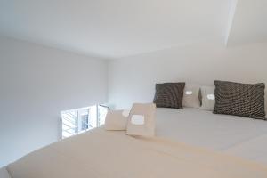 Una cama blanca con almohadas encima. en Tia Anica House II - apartment with terrace in central Fuseta beach village, en Fuseta