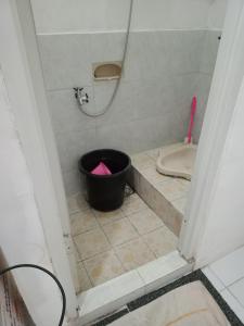 a bathroom with a bucket in a shower with a toilet at Mutiara Dieng in Wonosobo +9 photos