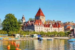 a large building sitting on top of a body of water at Appartement Les Jardins du Confort in Lausanne