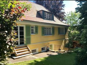 a yellow house with green shutters and stairs in a yard at Romantischer Villenteil in der Barock- und Musikstadt Ochsenhausen in Ochsenhausen