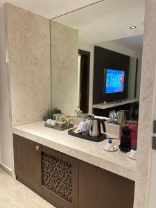 a kitchen with a counter with a sink and a mirror at Tajreed Suites in Riyadh