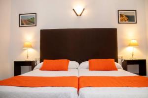 ein Schlafzimmer mit einem Bett mit zwei orangefarbenen Kissen in der Unterkunft Hostal El Capi in Zahora