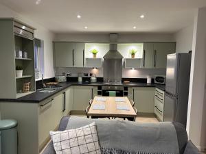 a kitchen with green cabinets and a table and a couch at Beach View Flat on Coastal Path in Llanelli