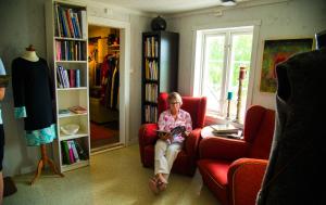 een vrouw die in een rode stoel een boek leest bij Lensmannsgården in Namdalseid