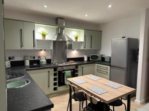a kitchen with a table and a refrigerator at Beach View Flat on Coastal Path in Llanelli