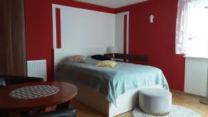 ウストカにあるDom wakacyjny u Mirkaのベッドルーム1室(赤い壁のベッド1台、テーブル付)