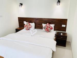 a bedroom with a bed with white sheets and red pillows at Mamta courtyard anjuna in Anjuna
