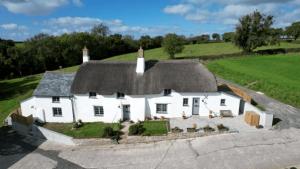 ein großes weißes Haus mit grauem Dach in der Unterkunft Cobb Cottage - HiddenDevon in Winkleigh