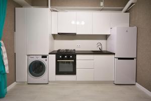 a kitchen with white cabinets and a washer and dryer at 1BR ultracentral Chișinău in Chişinău