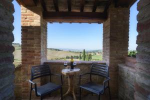 a patio with two chairs and a table with wine glasses at Agriturismo La Casellina in Monticchiello