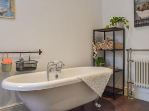 uma banheira branca num quarto com uma prateleira em The Swiss Cottage em Pickering