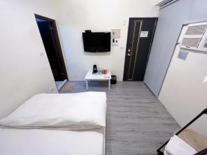 Zimmer mit 2 Betten, einem TV und einem Tisch in der Unterkunft FengChia FUN House in Taichung